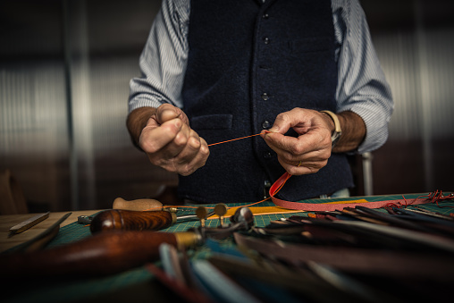 Close up shoot of an artisan working with leather in his laboratory.