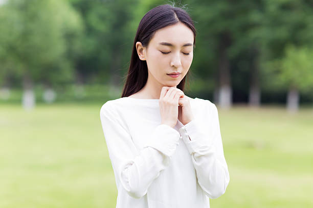 Portrait of a beautiful Chinese woman in white shirt stand in orchard in sunny day, cute girl praying for her lover, perfect side face.