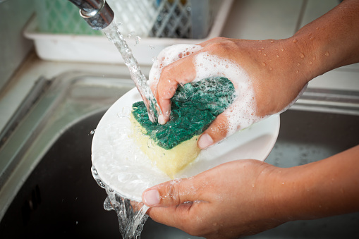 Mujer Lavando platos de la mano sobre el lavamanos de la cocina photo