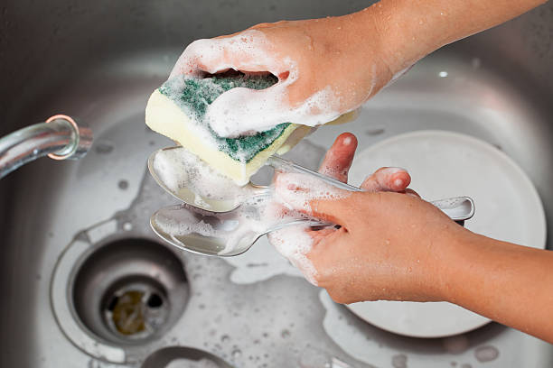 lavado de manos de mujer cuchara sobre el lavamanos de la cocina - silverware clean wet kitchen utensil fotografías e imágenes de stock