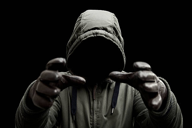 Mysterious killer A terrifying mysterious man wearing a hooded jacket with arms raised in a strangling or attacking pose. Shot against a black background. serial killings photos stock pictures, royalty-free photos & images