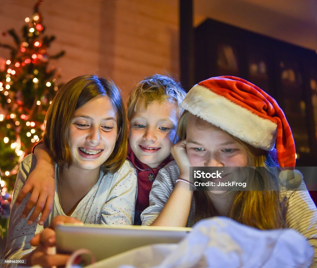 Christmastime, hermanos y hermanas divirtiéndose en una tableta digital - Foto de stock de Adolescente libre de derechos