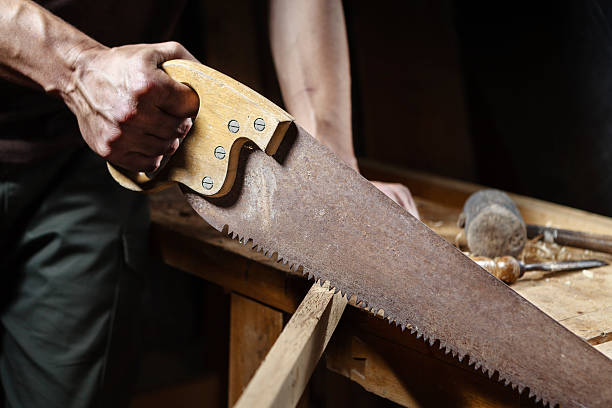 istock Carpenter sawing a board with a hand wood saw 488462778