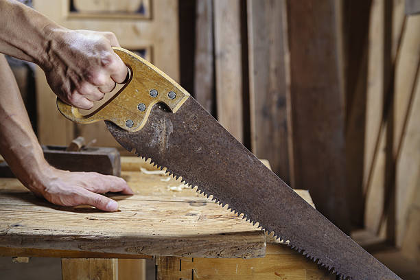 istock Carpenter sawing a board with a hand wood saw 488463006