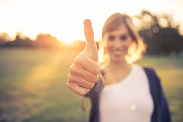 Young italian woman with thumbs up at the park