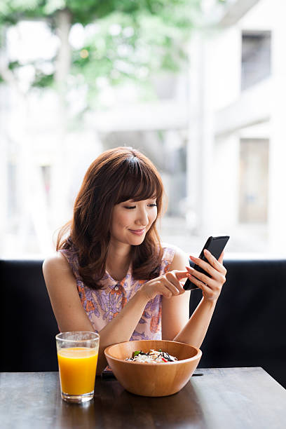 istock Attractive smiling girl using smartphone in a cafeteria 488470066