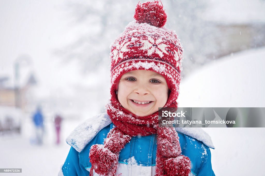 Linda little boy in blue traje de invierno, tocando al aire libre - Foto de stock de Invierno libre de derechos