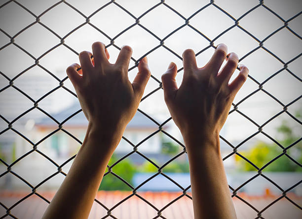 istock Girl in jail hands 488474716