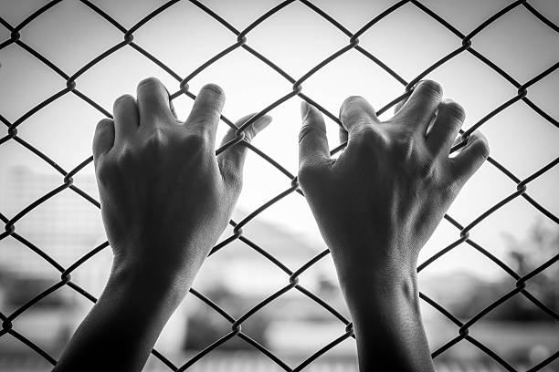 istock Girl in jail hands 488474750