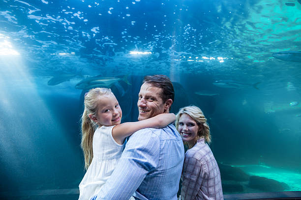 istock Happy family looking at camera behind a fish tank 488475630