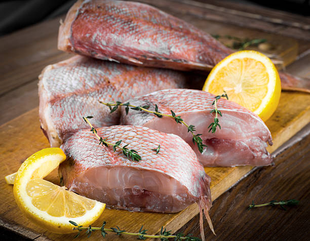 istock Sea bass with lemon on wooden board 488477789