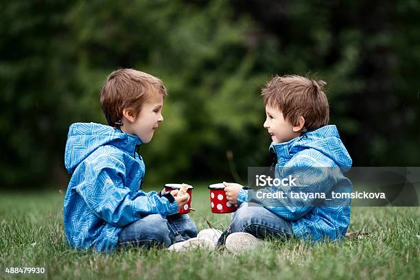 Two Beautiful Boys Brothers Sitting On A Lawn Autumn Time Stock Photo - Download Image Now