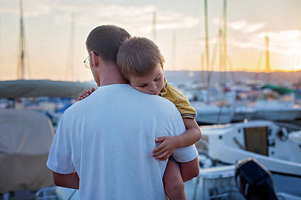 A Maori Man and Boy looking out to coastal marina by city.