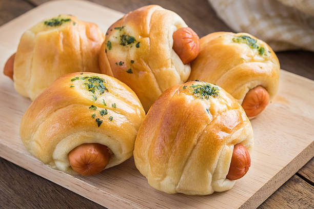 istock Bread roll with sausage on wooden plate 488484866