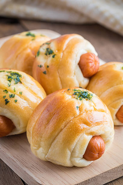 istock Bread roll with sausage on wooden plate 488485012