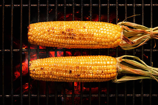 Whole Corn on grill Whole Sweet Corn with leaves grilled on hot coal fire. Seen from above sweetcorn stock pictures, royalty-free photos & images