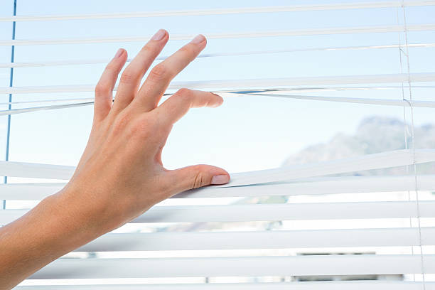 istock Curious person watching through venetian blind 488488462