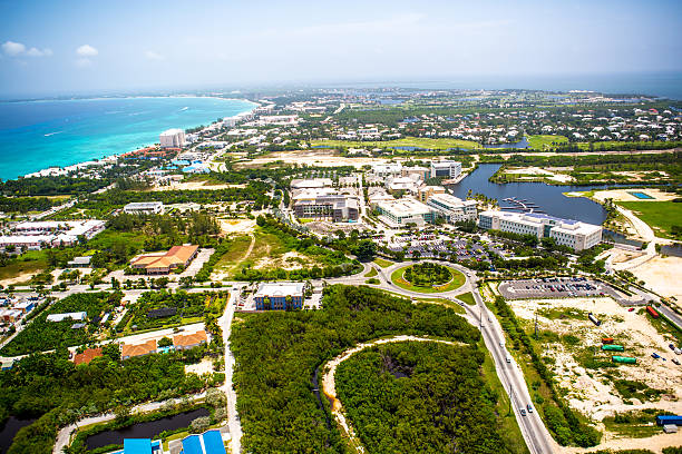 Aerial view of coastline of Grand Cayman, Cayman Islands A stunning aerial view over land of the coastline of popular vacation location Grand Cayman with it's clear aqua water and beautiful sand beaches. The beach stretches for miles. It is lush and tropical. It's a sunny perfect day in the Caribbean. grand cayman stock pictures, royalty-free photos & images