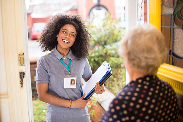 Smiling charity worker at the door Smiling sales representative shows her id card to a senior woman at the door saleswoman photos stock pictures, royalty-free photos & images