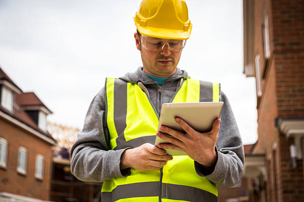 istock Young Caucasian Male Construction Worker Looking at Digital Tablet 488492012