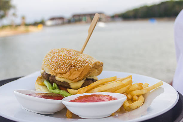 eating a burger sandwich in the redsea, el gouna, egypt, front of the port of el gouna with boats and sea view background