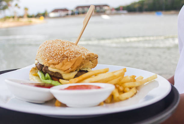 istock Close up waitress serving hamburger and fries in seaside 488495726