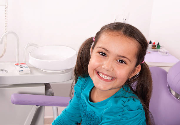 cute little girl in dental chair smiling stock photo