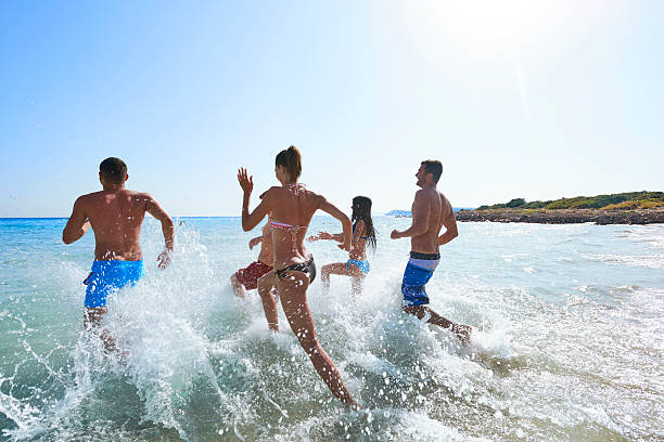 istock Group of young people running towards sea 488501958