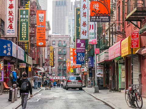 New York, USA - September 20, 2014: Tourists walks through a Chinatown street filled with posters and advertisements for various bars and restaurants