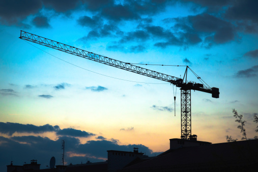 Silhouette of construction crane over houses