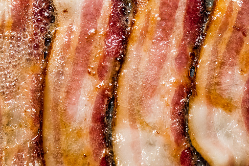 A macro view of bacon cooking on the stove.