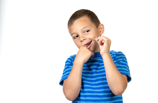 Boy is flossing teeth - isolated white background.