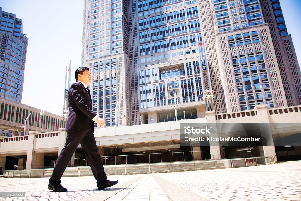 Japanese government worker walking to work Tokyo city hall Japanese government worker walking to work in front of Tokyo city hall. Tilted profile view, full length. ei is dressed in a suit and is looking purposefully ahead. Photographed in Shinjuku, Tokyo, Japan. Civil Servant Stock Photo