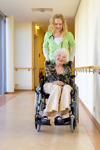 istock Nurse Assisting Elderly on Wheelchair at Corridor. 488510036