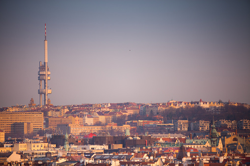 The skyline of Prague, taken on a hazy evening, with the Zizkov Television Tower dominating the baroque roofscape lower down the hill.
