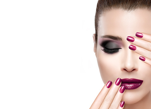 Beauty and Makeup concept. Beautiful fashion model woman with hands on face covering half mouth and one eye. Perfect skin. Professional manicure and makeup. smoky eyes. Fashionable eyelashes. High fashion portrait isolated on white with copy space for text.