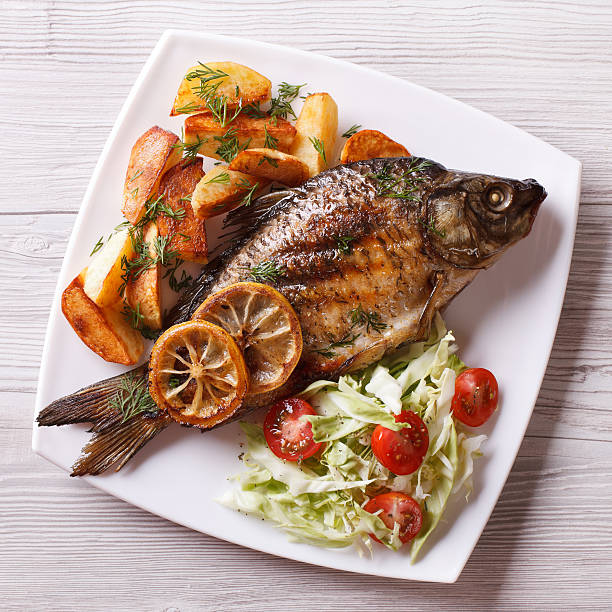 istock grilled fish with fried potatoes and salad top view, closeup 488513574