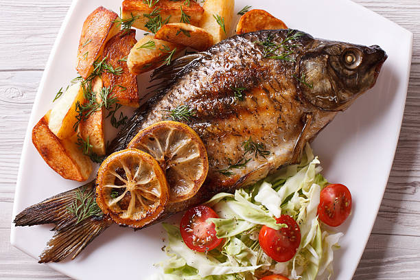 grilled fish with fried potatoes and salad horizontal top view