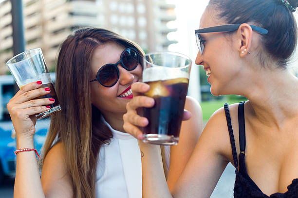 Portrait of beautiful young women drinking refreshment in the street.