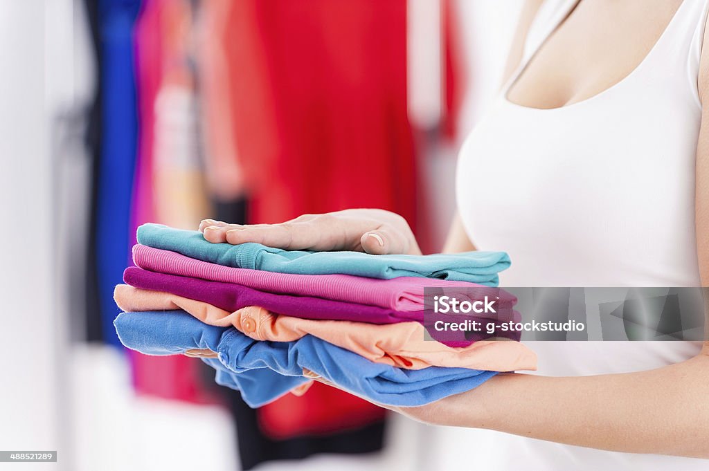 Stack of colorful clothes. Cropped image of woman holding stack of multi colored clothes Adult Stock Photo
