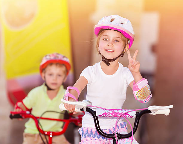Little girl sitting on pink bicycle outdoors. Kid with white long hair with sunglasses. Happy child with bike.