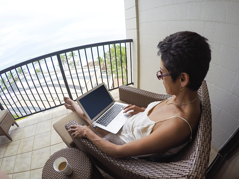 Woman on Laptop on Balcony on vacation in Hawaii