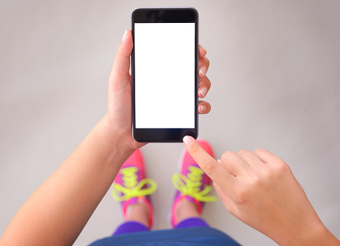 Woman wearing sports clothing and using blank white screen smart phone. 