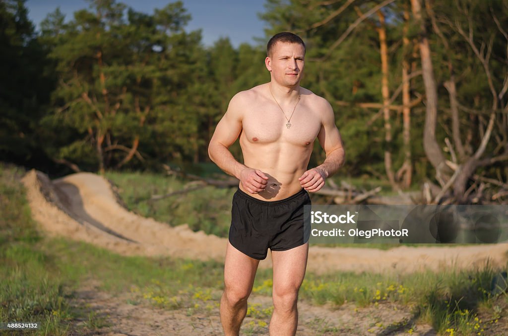 Young athlete running outdoors Young muscular man jogging outdoors on a summer evening. 2015 Stock Photo