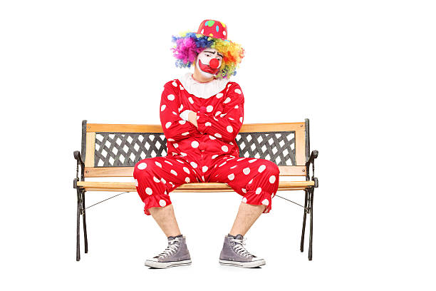 istock Unhappy clown sitting on a wooden bench 488525749