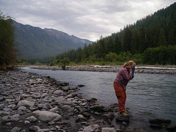Female Backpacker Washing Up at a River stock photo