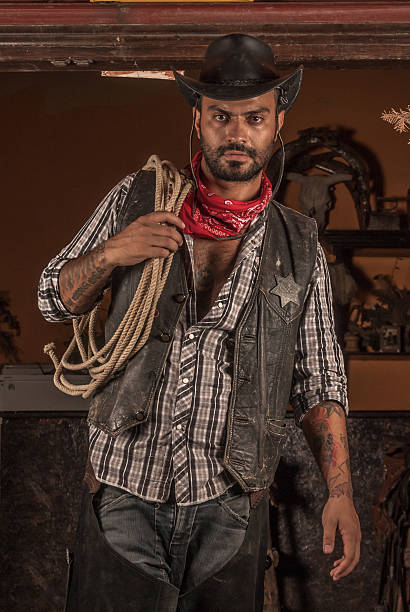 Cowboy holding lasso on his shoulder. Cowboy holding lasso on his shoulder and looking camera giving pose. shoulder tattoo designs for men stock pictures, royalty-free photos & images