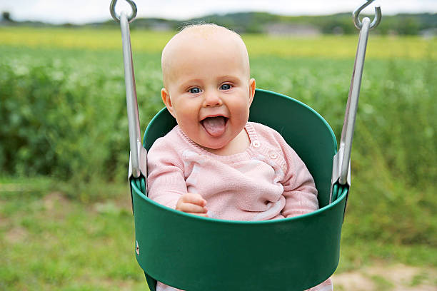 happy baby mädchen schaukeln auf dem spielplatz - 5 month old stock-fotos und bilder