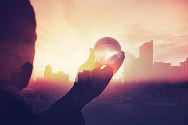 Business man in suit with cityscape montage. Business man in suit with cityscape montage. The man is unrecognizable and you cannot see his face. He is superimposed onto a city skyline at sunset. He is holding a world map globe like a crystal ball. Success, vision concept with copy space. concepts topics stock pictures, royalty-free photos & images