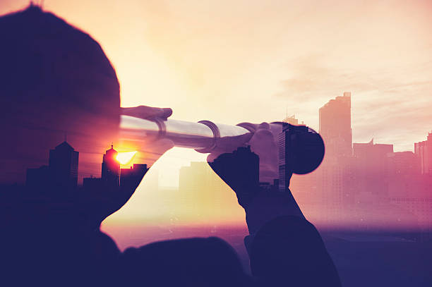 Business man in suit with cityscape montage. Business man in suit with cityscape montage. The man is unrecognizable and you cannot see his face. He is superimposed onto a city skyline at sunset. He is holding a telescope looking into the city. Success, vision concept with copy space. the way forward stock pictures, royalty-free photos & images